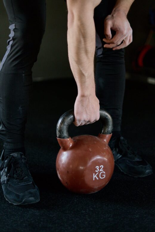 person in black pants holding red kettlebell