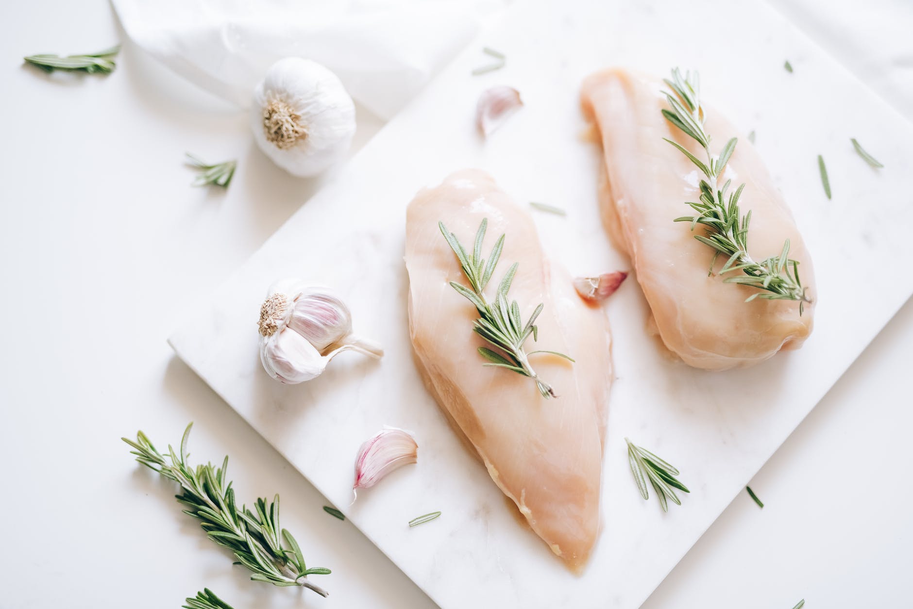 top view of rosemary sprigs on raw chicken breasts