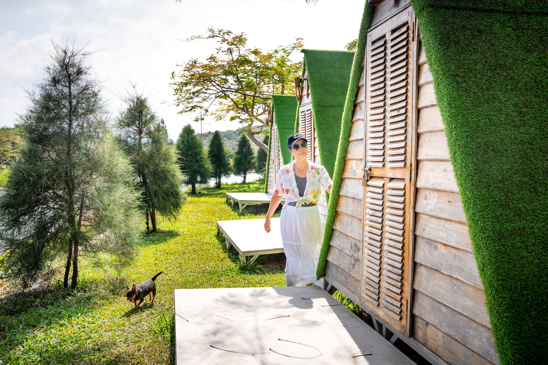 woman with dog standing near porch of house in countryside