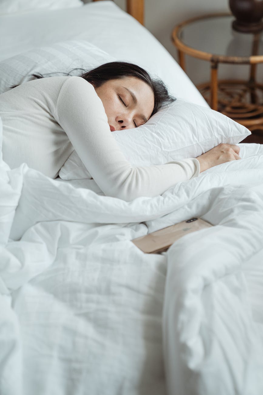 woman in white long sleeved shirt lying on bed