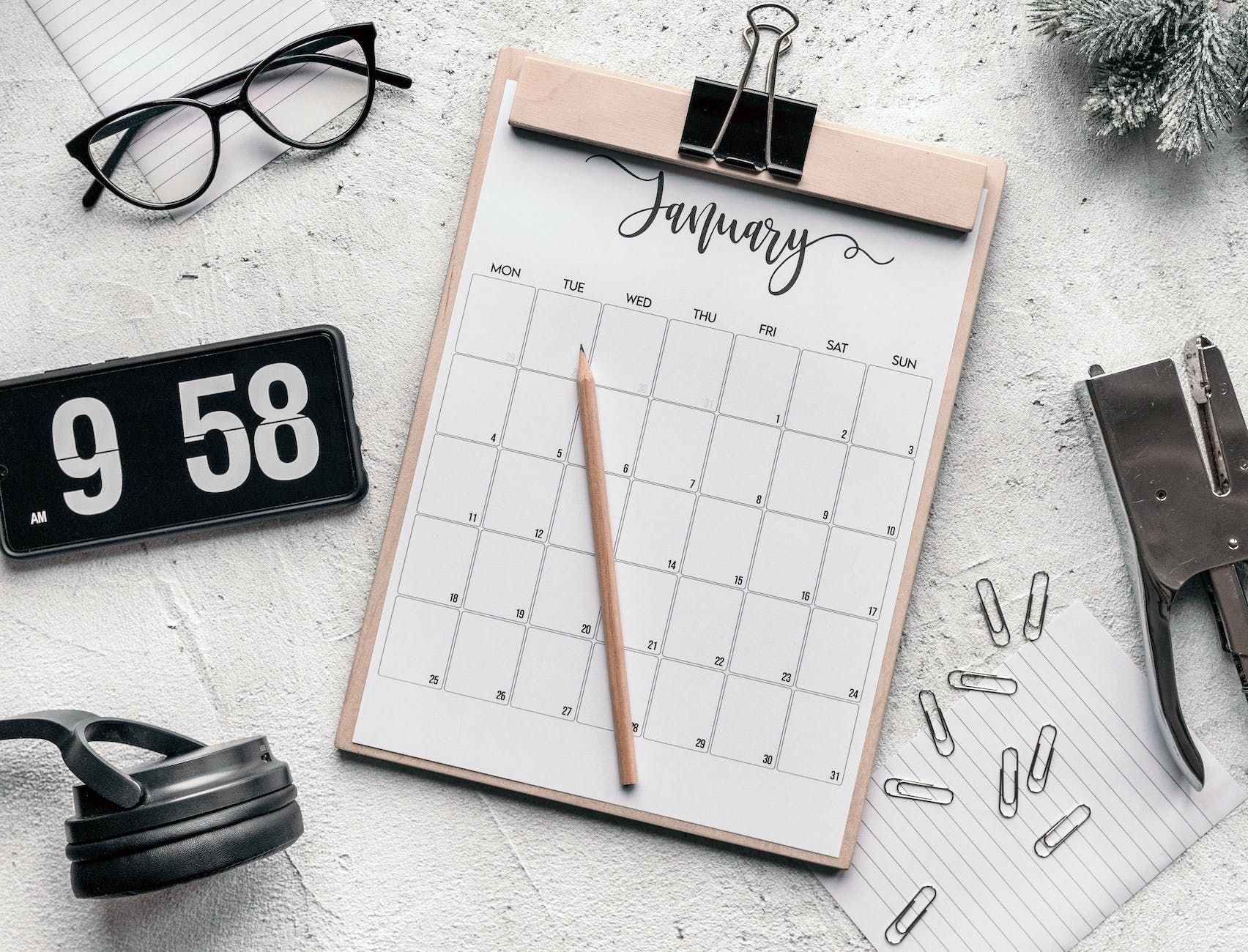 clipboard with calendar placed on desk amidst stationery