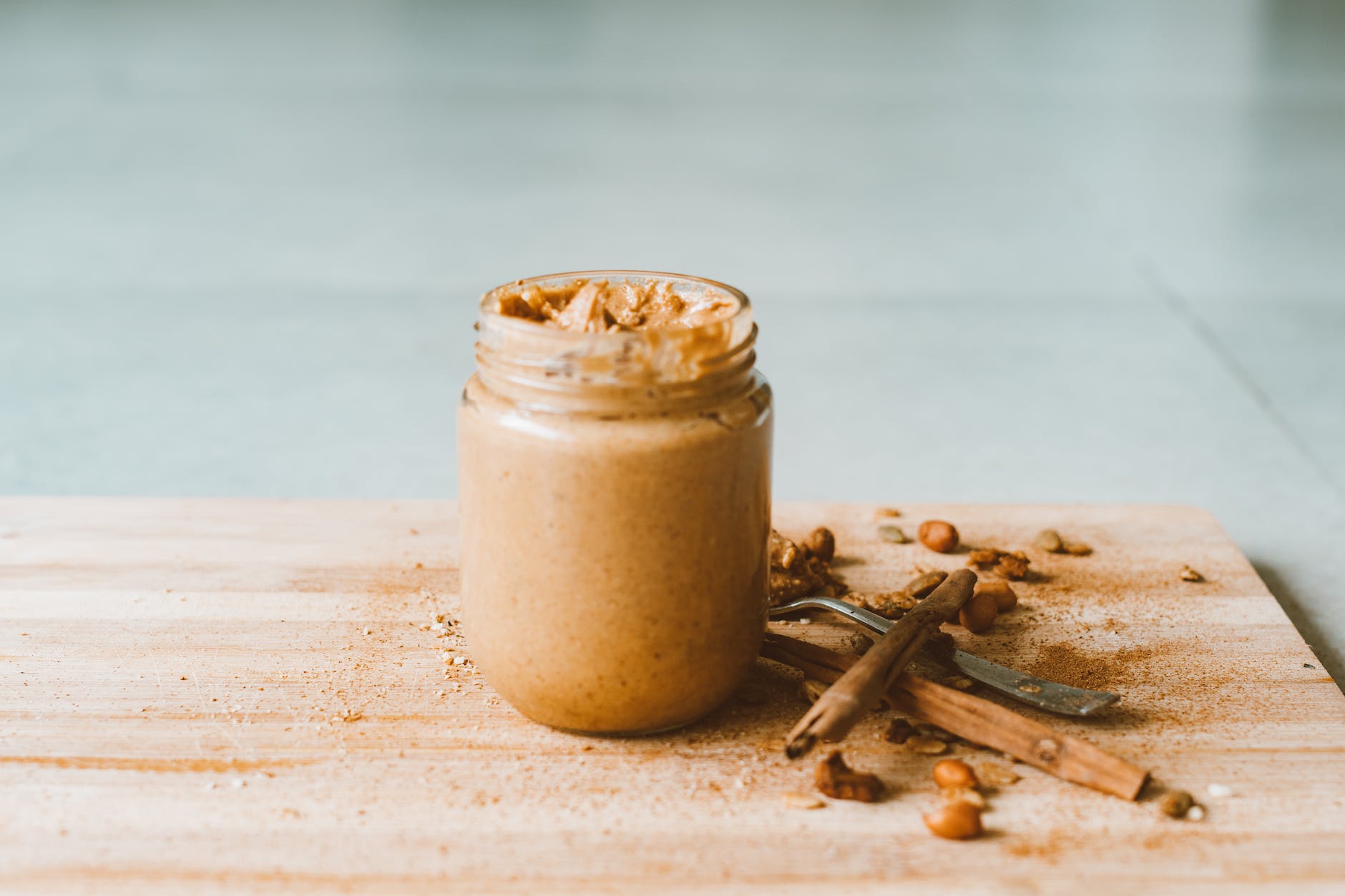 glass jar of peanut butter on wooden cutting board