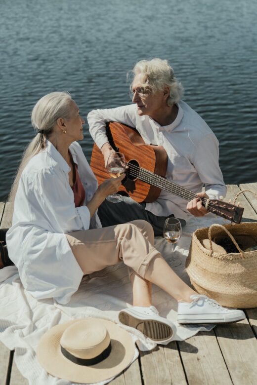 an elderly couple sitting on a wooden dock