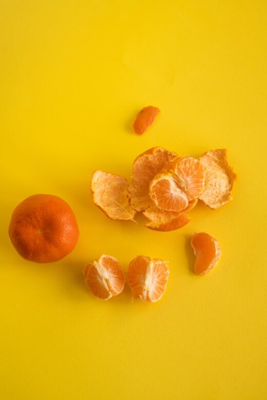 mandarin near slices and peel on yellow background