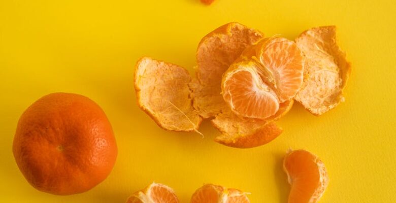 mandarin near slices and peel on yellow background