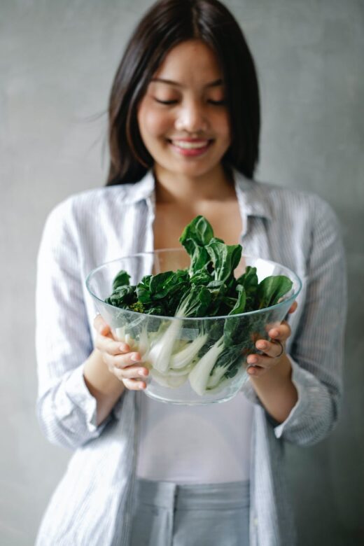 cheerful asian woman with bowl of bok choy