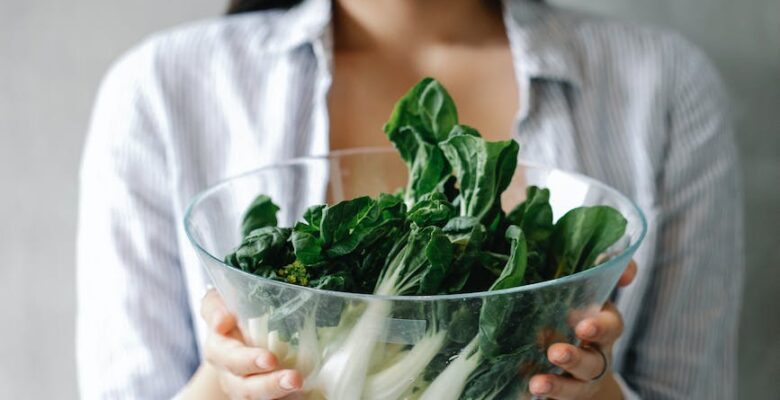 cheerful asian woman with bowl of bok choy