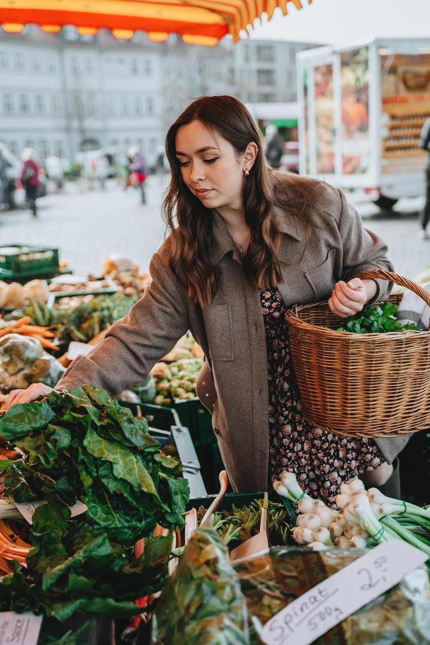 photograph of a woman buying green vegetables