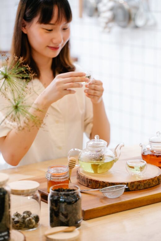 smiling woman brewing tea in glass teapots in the kitchen