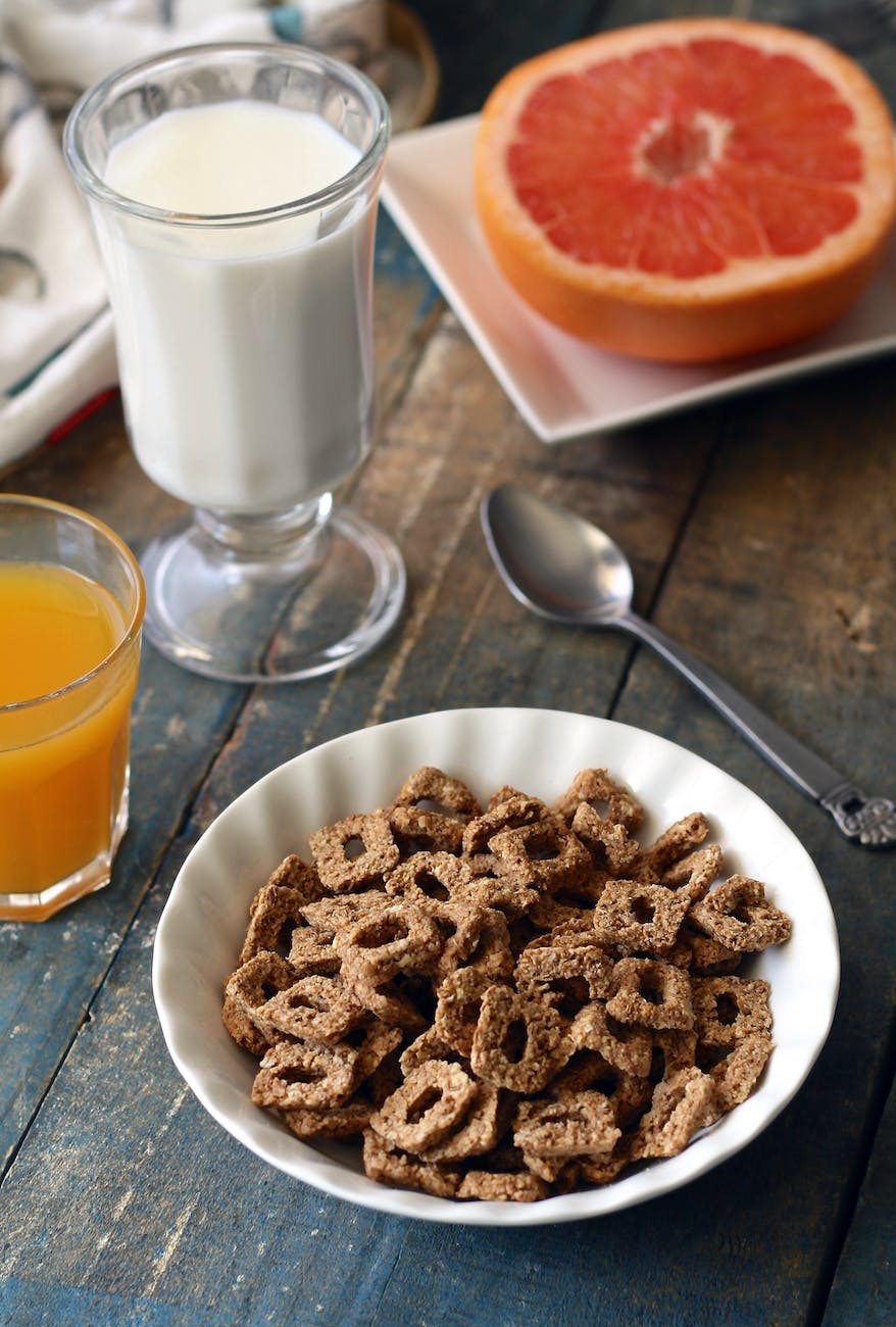 chocolate cereal on white bowl near glass of milk