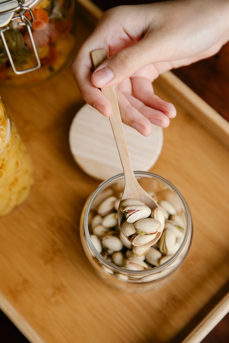 unrecognizable person demonstrating spoon with pistachios