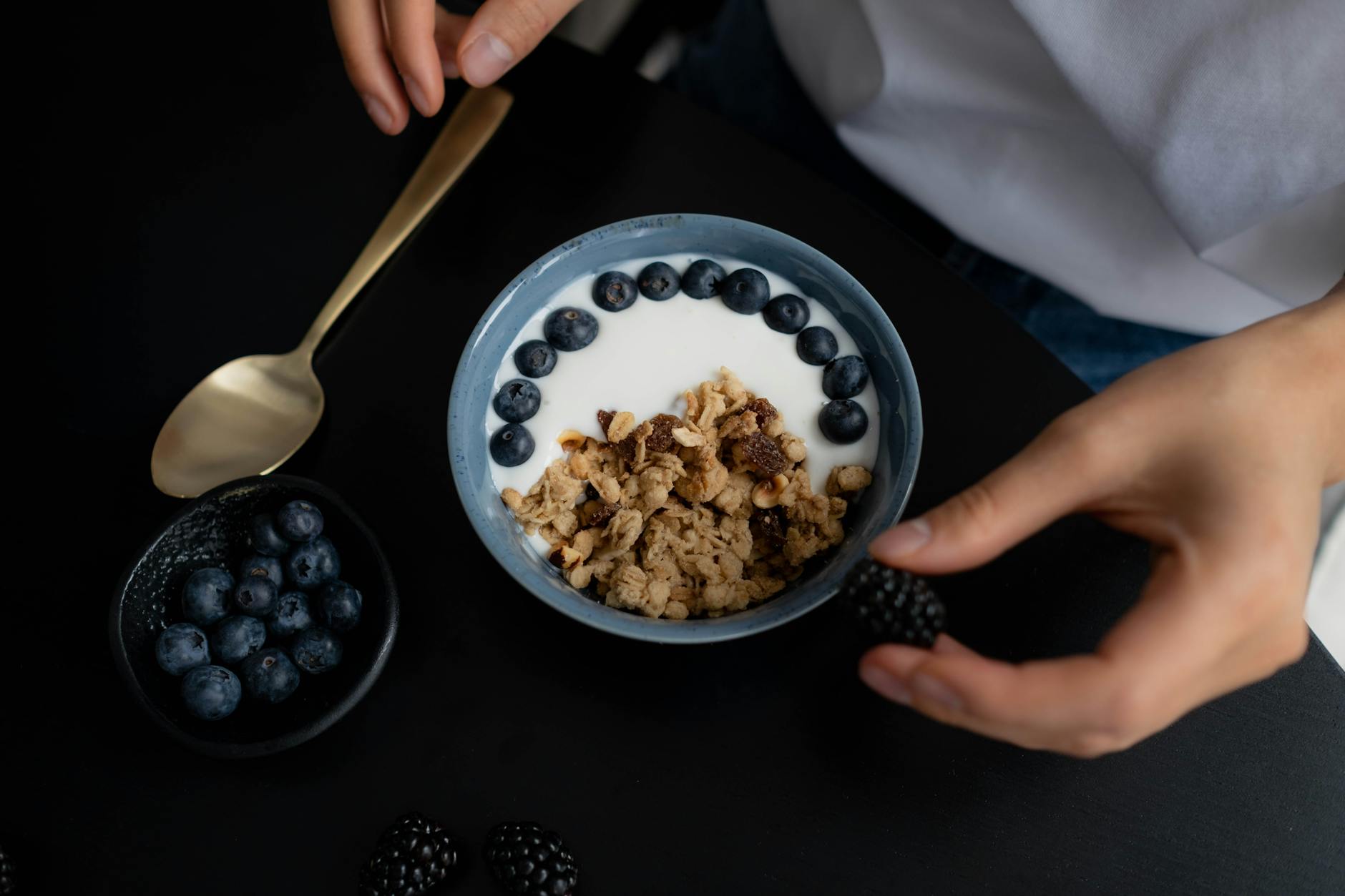 bowl with granola milk and blueberries on black table
