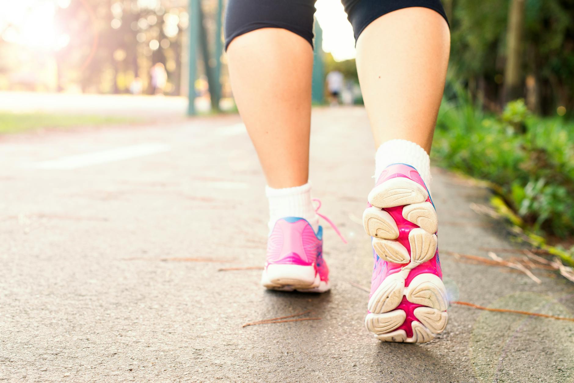 photo of woman wearing pink sports shoes walking