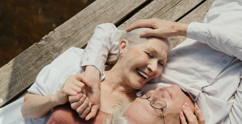 an elderly couple lying on a wooden dock