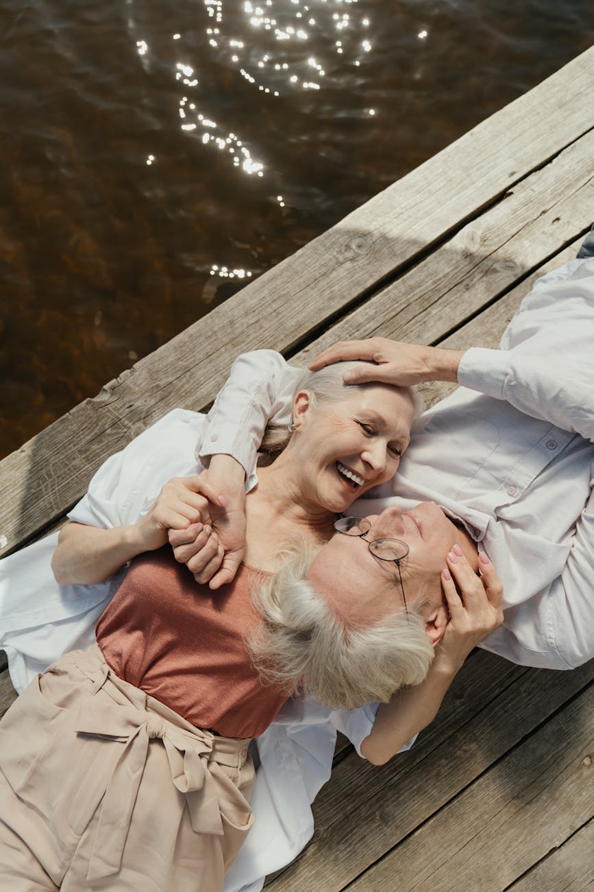 an elderly couple lying on a wooden dock