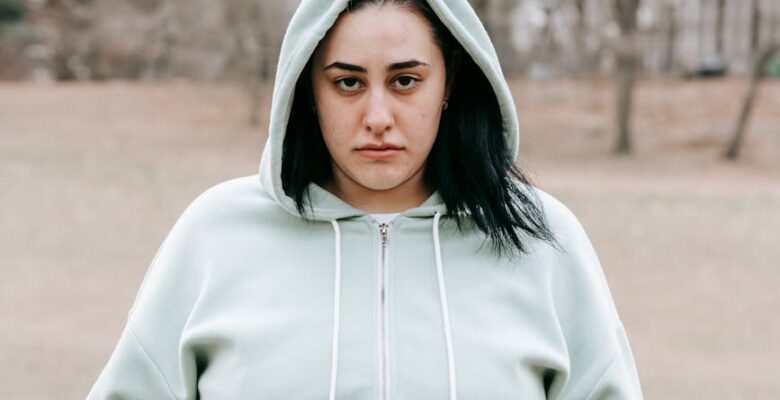 a woman in sportswear touching her belly in park