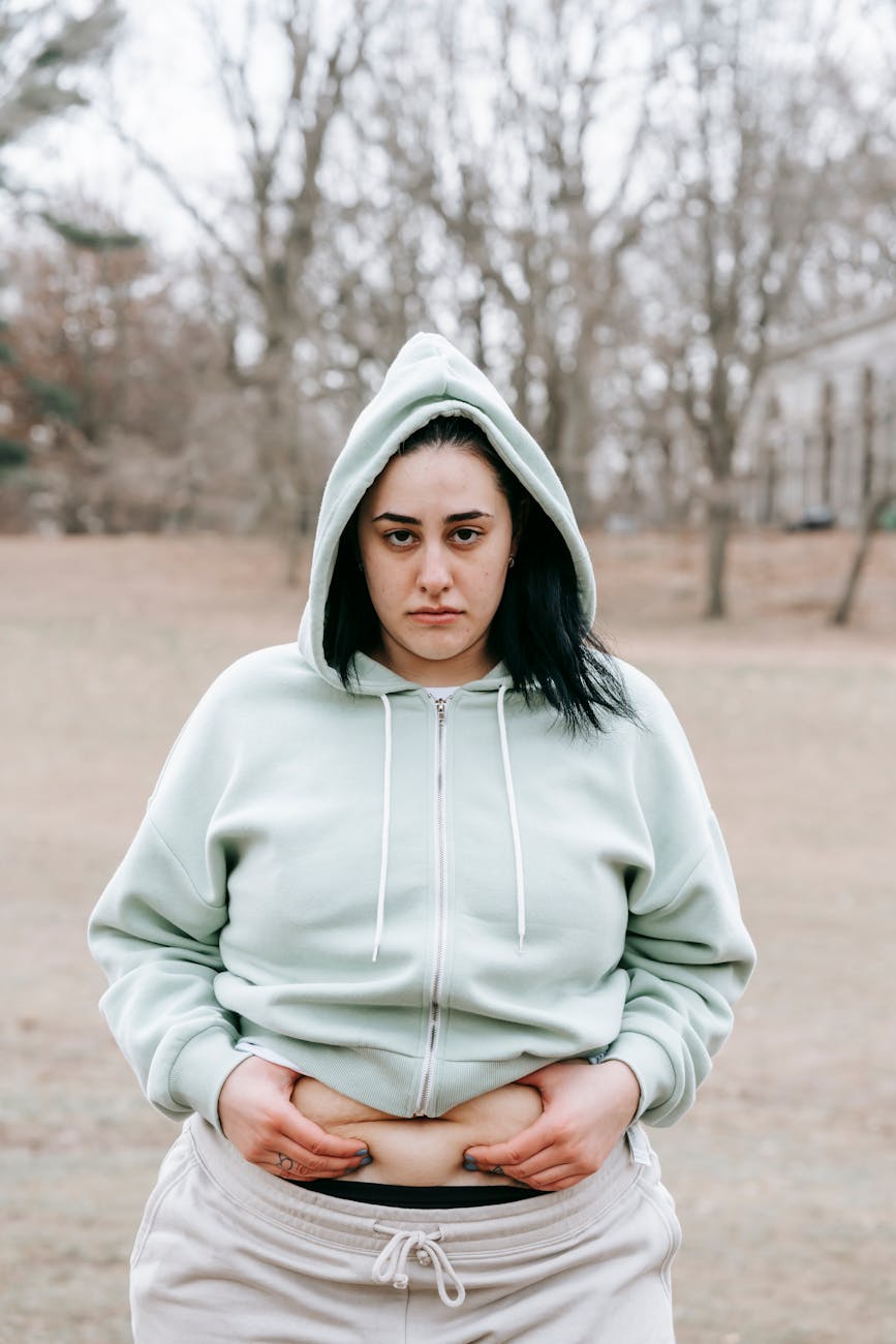 a woman in sportswear touching her belly in park