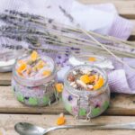 delicious desserts in glass jars beside a pair of spoons and textile